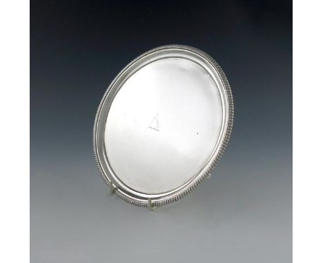 A George III silver waiter, by Thomas Wallis, London 1809, circular form, gadroon border, the centre with a crest, on three f