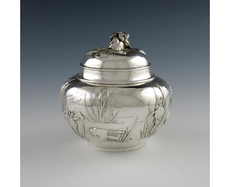 A Japanese silver tea caddy, maker's mark of S in a circle within a fan shaped punch, circular form, embossed with pond scene