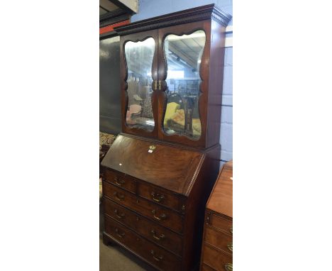 Mahogany bureau cabinet, the top with two mirror doors enclosing an interior with adjustable shelving over a typical fall fro
