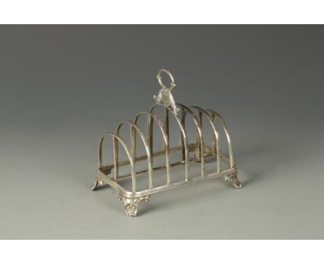 A VICTORIAN TOAST RACK of seven arched bars, with central loop handle, monogrammed, on bracket feet, by Henry Wilkinson & Co.