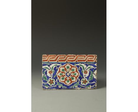 AN "ISNIC"POTTERY TILE with glazed polychrome floral decoration on blue ground, with the remains of an old collectors label, 