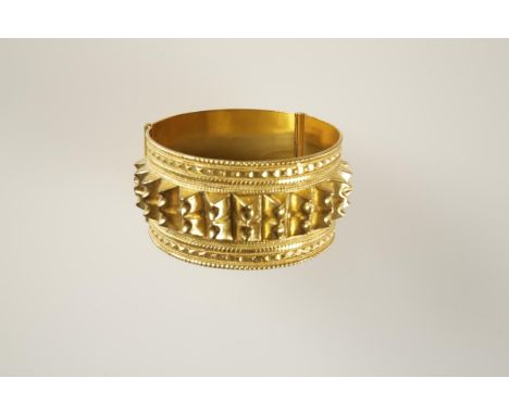 A MIDDLE EASTERN GOLD CUFF BANGLE, decorated with bands of engraved patterns enclosing a central raised pointed stud panel, h