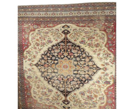 A KERMAN LAVAR CARPET, the ivory field with a large indigo reserve enclosing a floral pole medallion, light crimson spandrels