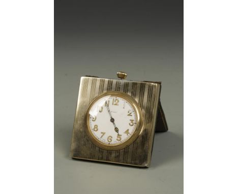 A SILVER GILT TRAVELLING CLOCK, the round dial with Arabic numerals, raised set in a square engine-turned silver gilt case, w