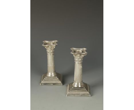 A PAIR OF CANDLESTICKS of corinthian column form, with pull-off beaded sconces, on stepped square bases, filled, by William H