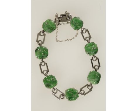 A 9CT WHITE GOLD AND JADE BRACELET claw-set with seven octagonal shaped plaques of carved jade, interspaced with geometric li
