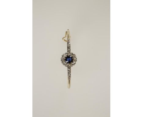 A LATE VICTORIAN SAPPHIRE AND DIAMOND HINGED BANGLE claw-set with a single cushion-shaped sapphire within a border of ten cus