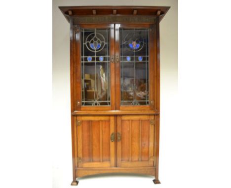 An early 20th century Arts & Crafts walnut cabinet, copper panel to top inscribed 'Studies Serve For Delight', upper section 