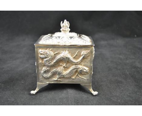 A Chinese embossed white metal rectangular tea caddy on paw feet, decorated with dragons, with Buddhist deity to lid - L11cm,