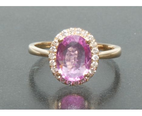 A pink sapphire and diamond cluster ring, central oval pink sapphire approx 1.60ct, surrounded by a band of twenty two round 