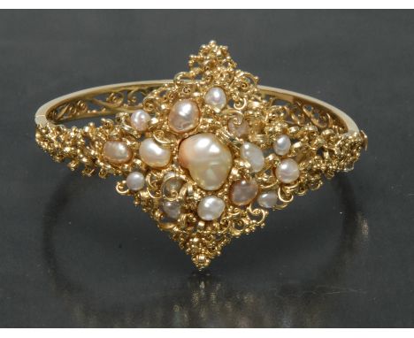 A blister pearl and 15ct gold hinge bangle, naturalistic scrolling crest, inset with sixteen mixed cream, white and grey blis