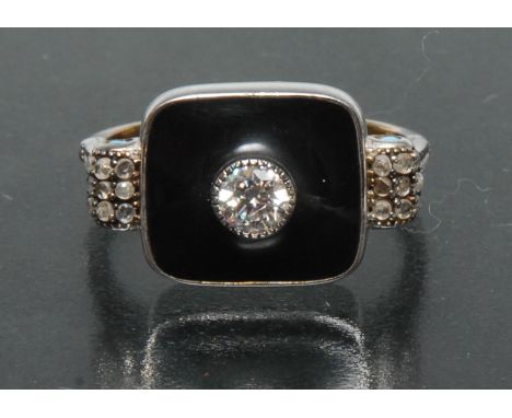 An Art Deco diamond, turquoise and black enamel dress ring, central round old brilliant cut diamond approx 0.21ct, upon a bla