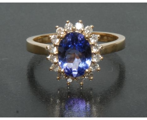 A tanzanite and diamond cluster ring, central oval violet blue tanzanite approx 1.49ct, surrounded by a band of sixteen round