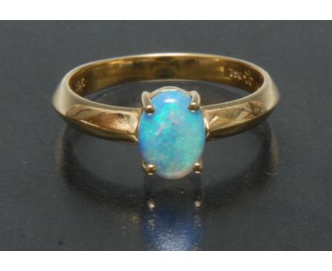 An 18k yellow gold Australian blue black opal cabochon ring, oval opal flashing vibrant blue,green and violet colour play, ap