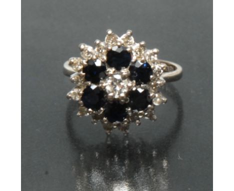 A sapphire and diamond floral cluster ring, central round brilliant cut diamond approx 0.15ct, surrounded by a band of six de