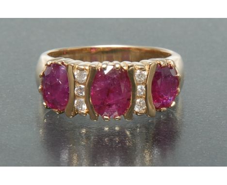 A ruby and diamond ring, inset with three large oval pinky red rubies, each divided by a row of three round brilliant cut dia