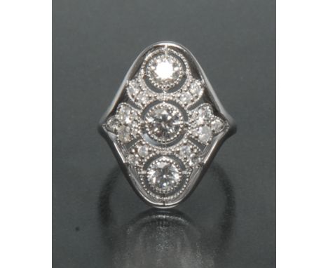 An Art Deco style diamond ring, inset with three round brilliant cut principle and twenty smaller pave set diamonds, total es