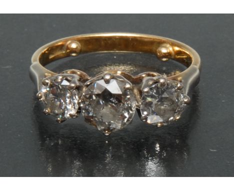 A diamond trilogy ring, central round old brilliant cut diamond approx 1.0ct, flanked either side by a similar smaller diamon