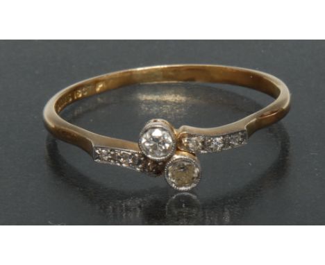 An Art Deco diamond and white sapphire crossover ring, central pair of twist set round old cut diamonds, above three stone wh