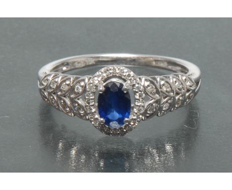 A sapphire and diamond dress ring, central oval mid blue sapphire approx 0.55ct, claw set above a surrounding band of twenty 