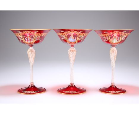 A SET OF THREE VENETIAN RUBY GLASS CHAMPAGNE COUPES,&nbsp;with dish bowls on wrythen baluster stems and domed circular folded