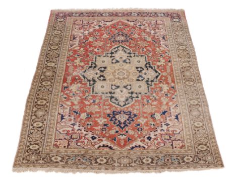  A Heriz carpet,   the madder field with central navy and cream medallion, cornered by spandrels,    aproximately 316 x 228cm