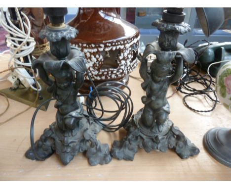 A pair of 20th century cast metal lamp bases, in the form of boys holding a Lotus flower above their heads, on base with thre