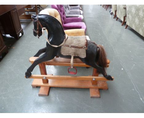 A vintage rocking horse painted black with saddle and stirrup irons, 68cm to wither.