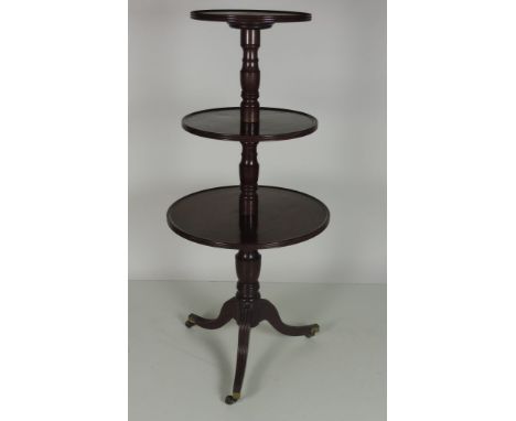 A late Georgian period circular mahogany three tier Dumbwaiter, with turned pillar supports on a tripod base with outsplayed 