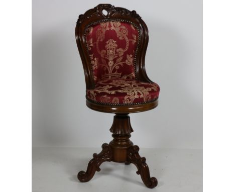 A Victorian mahogany Music Chair, the curved back carved with scrolling foliage, above a circular padded seat on a tripod bas