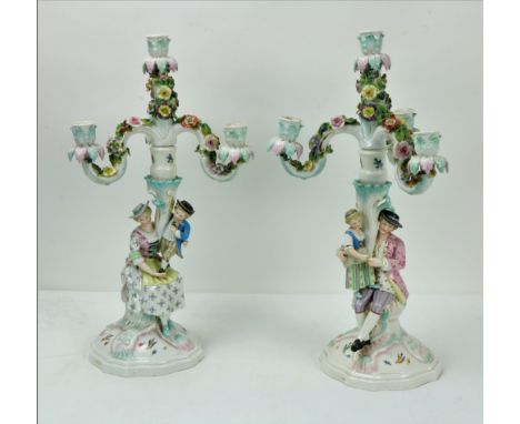 A fine pair of Sitzendorf figural porcelain three branch, four light Candelabra, with flower encrusted arms, one with mother 