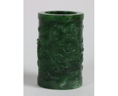 A fine Chinese natural green jade Dragon Brush Pot, carved with two dragons in relief with Greek key banded base and rim, 3 1