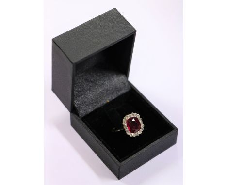 An attractive Ladies gold Ring, with large ruby type inset stone surrounded by 18 cut diamonds. (1)