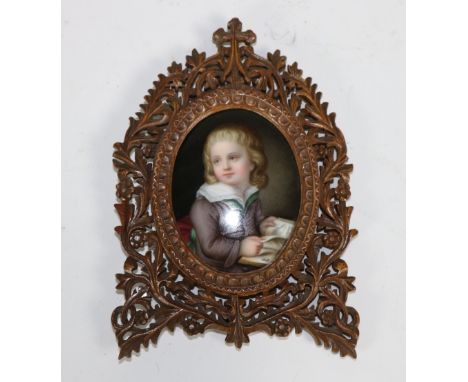 A 19th Century German oval miniature Portrait, of "A young Boy with Book"on porcelain in ornate fret carved frame with scroll