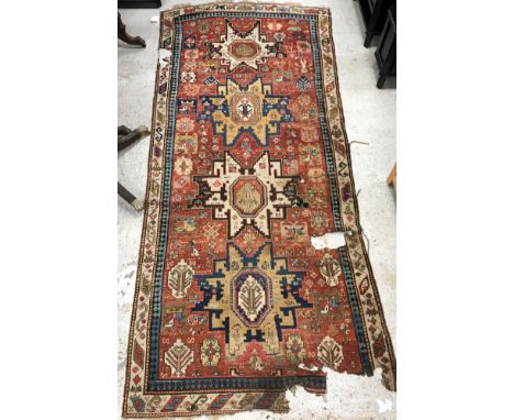 A vintage Caucasian runner, the central panel set with geometric medallions on a red ground, with stylised floral, figural an