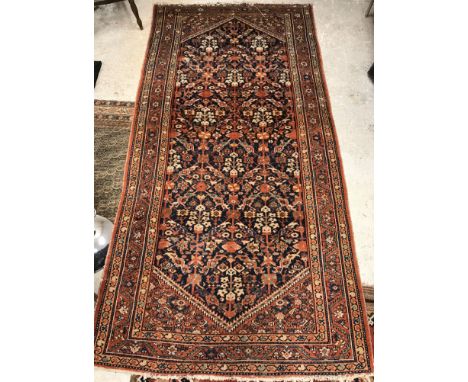 A Persian carpet, the central panel set with all over floral decoration on a blue ground, within a stepped terracotta and ora