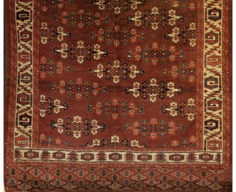 A BOKHARA TYPE SMALL CARPET, the aubergine ground worked with stylized ivory, dark blue medallions within serrated leaf ivory