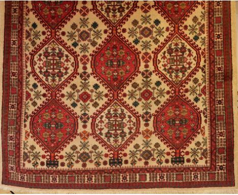 A NORTHWEST PERSIAN CARPET, the ivory ground with three rows of hexagonal medallions, with hooked boteh borders and floral pa