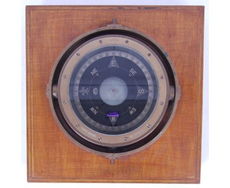 An early 20th century ship's gimball deck compass, mounted within a wooden viewing case. Various patent marks to the rim. PAT