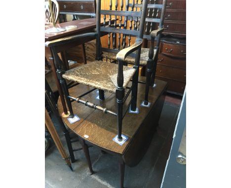 An 18th century oval joined oak gate leg table with pad feet, together with four spindle back and rush seated Lancashire chai