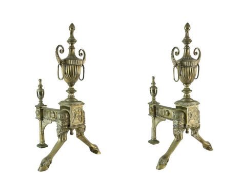 A pair of ornate Neo-classical brass andirons. Early to mid 19th century, the urn finials with ring handles, raised on cloven