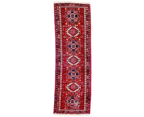 An Iranian Karaja wool runner. Seven central medallions on red ground, 200cm x 63cm.