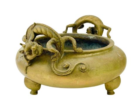A Chinese polished bronze 'dragon' tripod censer. Qing dynasty, heavily cast, with scaly dragon handles, and raised on three 