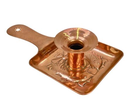 A Newlyn copper chamber candlestick. With a square base, repousse decorated with two fish, with a shaped handle, stamped mark