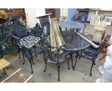 A cast alloy garden table, six chairs, bench ends and small table