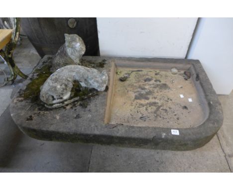 A large stone garden trough and two cat ornaments