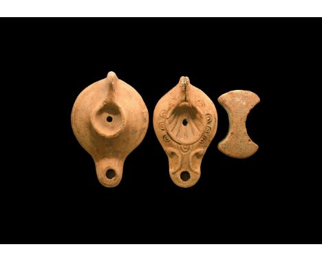 2nd-3rd century AD. A group of three terracotta items comprising: one plain oil lamp, one decorated with shell motif, a piece