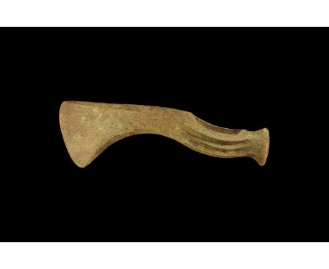 9th-7th century BC. A bronze axe head with wide triangular-section blade, three raised ribs to the socket, a flattened knob t