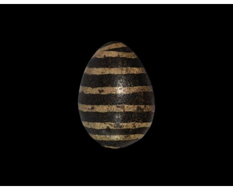 9th-11th century AD. A glazed hollow ceramic egg with a hole to the underside, dragged yellow lines to the outer face. See ww