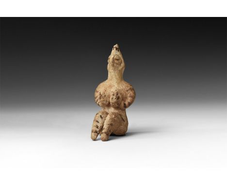 4th millennium BC. A ceramic figurine of a female with legs folded, arms supporting the breasts, conical head with pinched fa